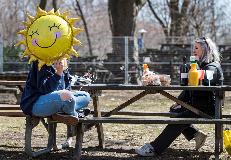 Caroline Filion, tenant un ballon en forme de soleil, discute avec son amie Elisabeth Tanguay au parc La Fontaine lors de la troisième vague de la pandémie de COVID-19, à Montréal.