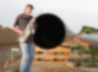 Un gars joue du saxophone en duo avec un gazoduc